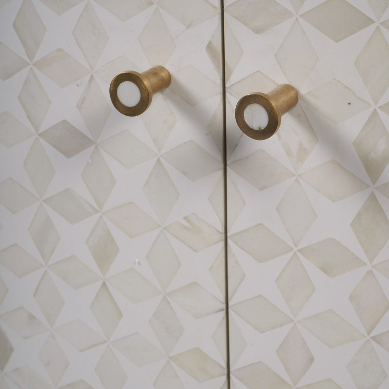 Pair of gold cabinet knobs on a geometric-patterned wall.
