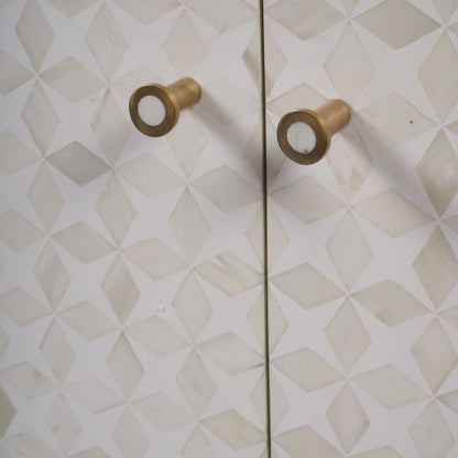 Pair of gold cabinet knobs on a geometric-patterned wall.