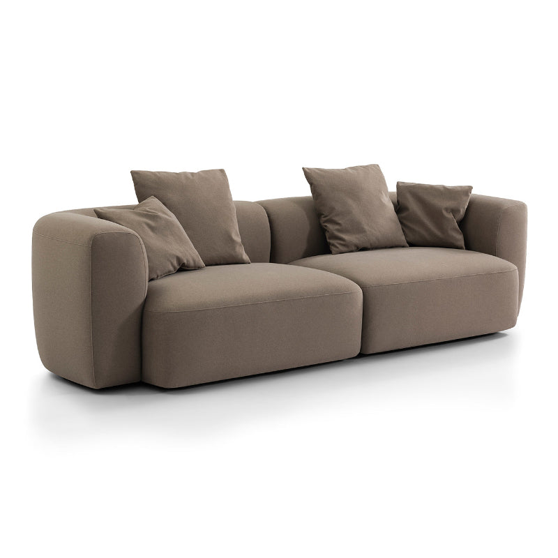 A modern low-profile modular sofa in a warm taupe-brown fabric, featuring four matching throw pillows, shown on a clean white background.