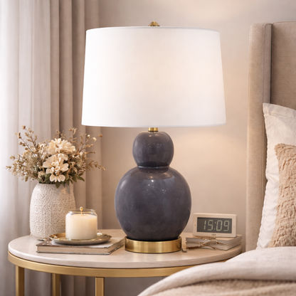 Decorative table lamp on a nightstand next to a bed with pillows