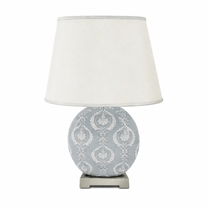 Decorative table lamp with a patterned base and white shade on a white background