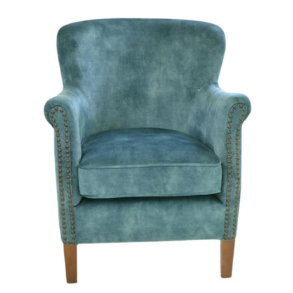 A classic wingback armchair upholstered in textured teal blue velvet, featuring rolled arms with brass nailhead trim and light brown wooden legs, shown against a plain white background.