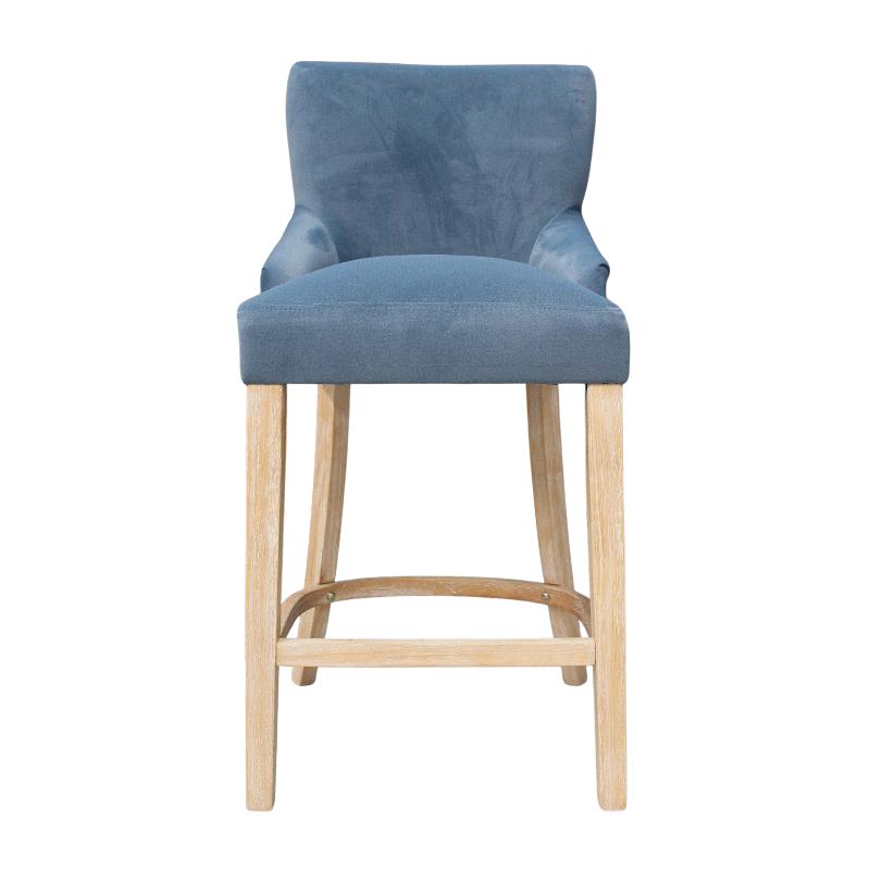 A blue velvet upholstered bar stool with light natural wood legs and a footrest, shown against a plain white background.