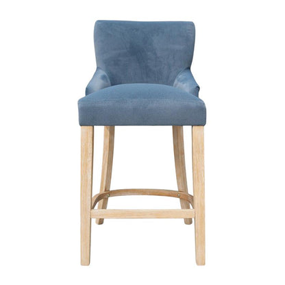A blue velvet upholstered bar stool with light natural wood legs and a footrest, shown against a plain white background.