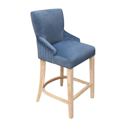 A blue velvet upholstered bar stool with a light natural wood frame and silver nailhead trim on the armrests, shown against a plain white background.