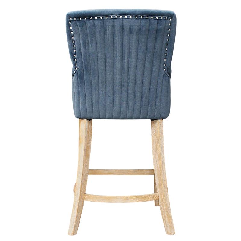 A single upholstered bar stool shown from the back, featuring a blue-gray ribbed velvet backrest with silver nailhead trim and a light natural wood leg frame on a white background.