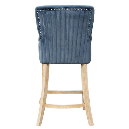 A single upholstered bar stool shown from the back, featuring a blue-gray ribbed velvet backrest with silver nailhead trim and a light natural wood leg frame on a white background.