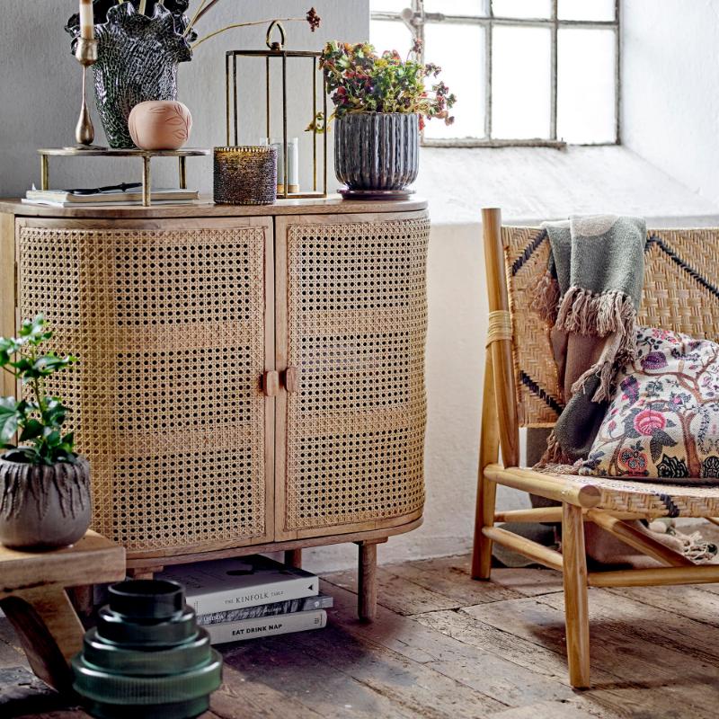 Rattan cabinet in a room with a window, plants, and a chair.