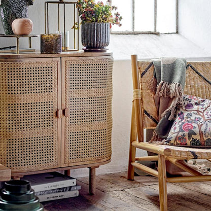 Rattan cabinet in a room with a window, plants, and a chair.