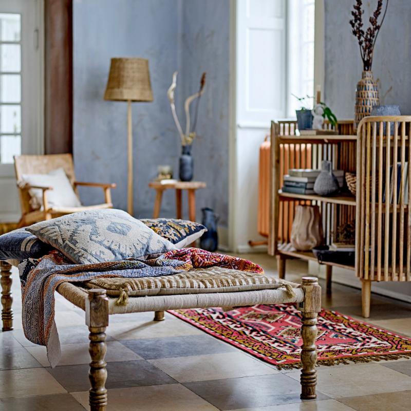 Living room with wooden bench, pillows, and decorative items in a bright room.