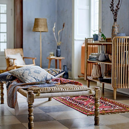 Living room with wooden bench, pillows, and decorative items in a bright room.