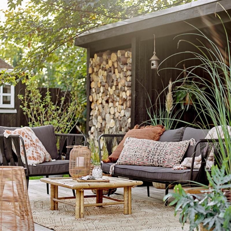 Outdoor patio with furniture, plants, and a stone wall.
