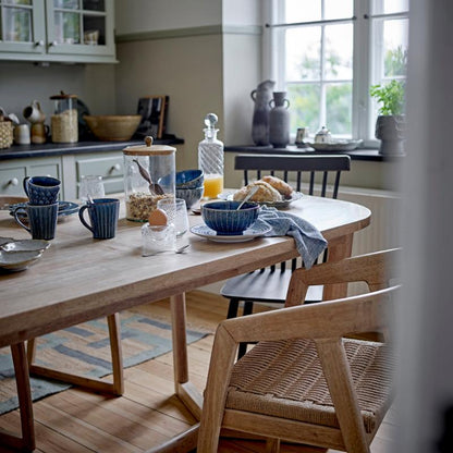 Dining area with wooden table and chairs, kitchen in the background