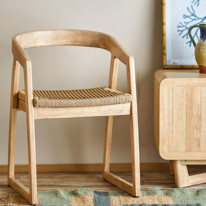 Wooden chair with woven seat in a room with framed artwork on the wall.