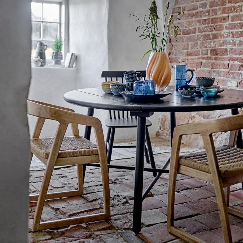 Dining area with a round table and chairs in a room with brick walls and a window.