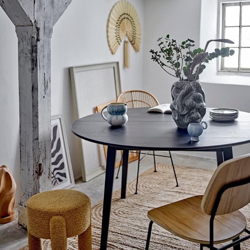 Dining room with a black round table, wooden chairs, and decorative elements.