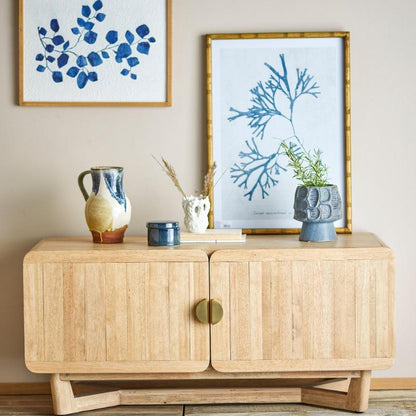 Wooden sideboard with decorative items and framed artwork on a wall.