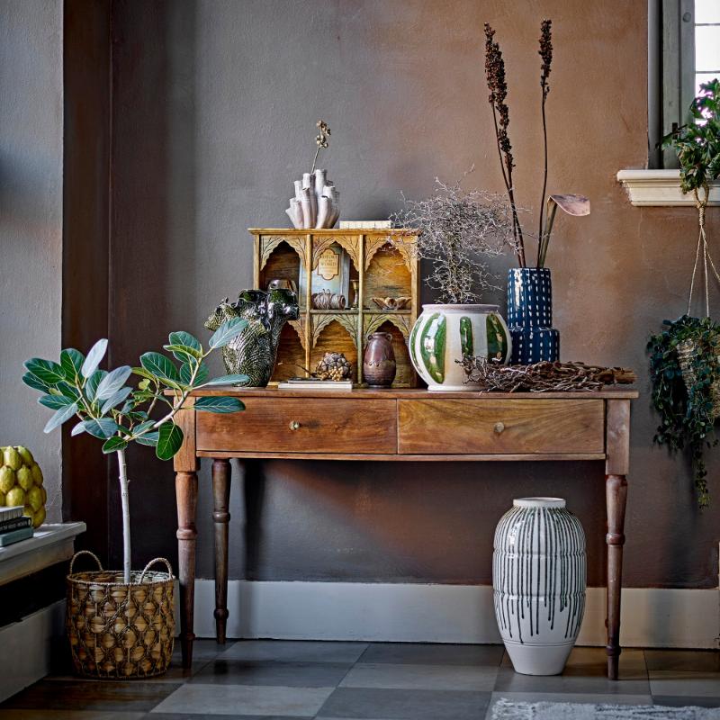 Decorative console table with various items against a textured wall.
