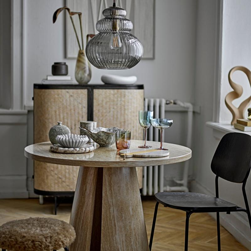 Round wooden table with decorative items in a room with a chair and lamp.