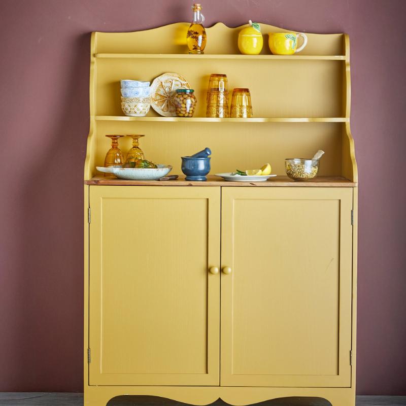 Yellow cabinet with decorative items against a purple wall