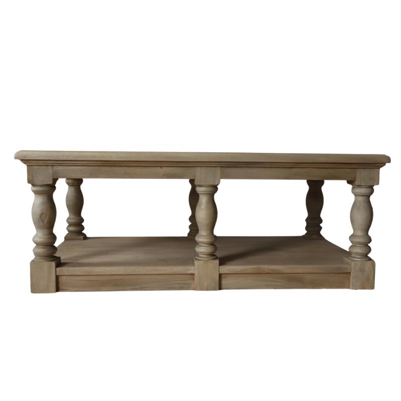 A light natural wood coffee table with a single rectangular top, four turned legs, and a lower shelf, set on a textured beige rug against a neutral wall.