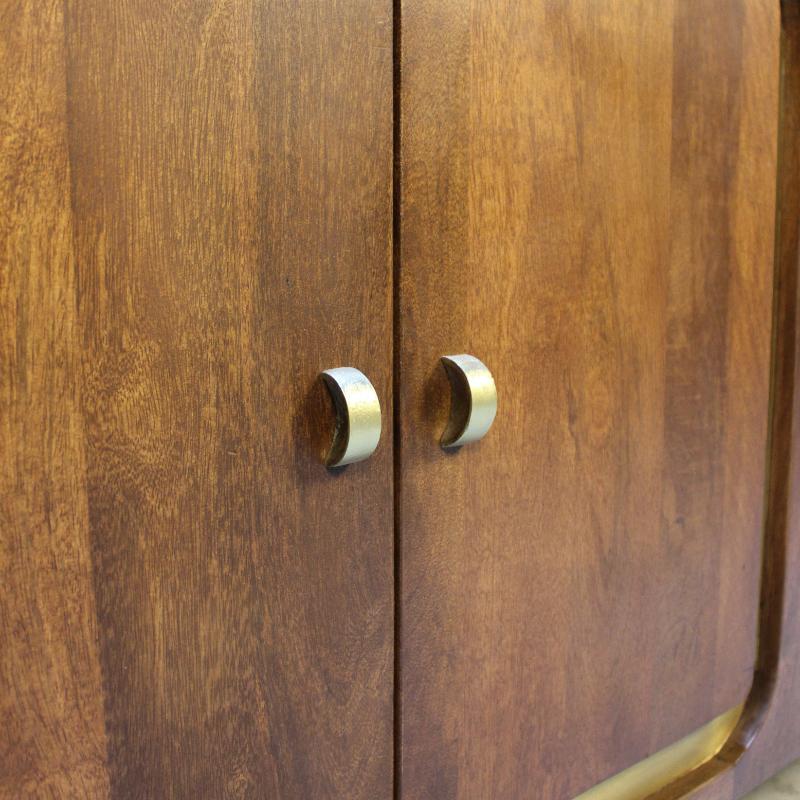 Close-up of a wooden cabinet door with two curved metallic handles, showing warm medium-brown wood grain and brushed silver hardware.