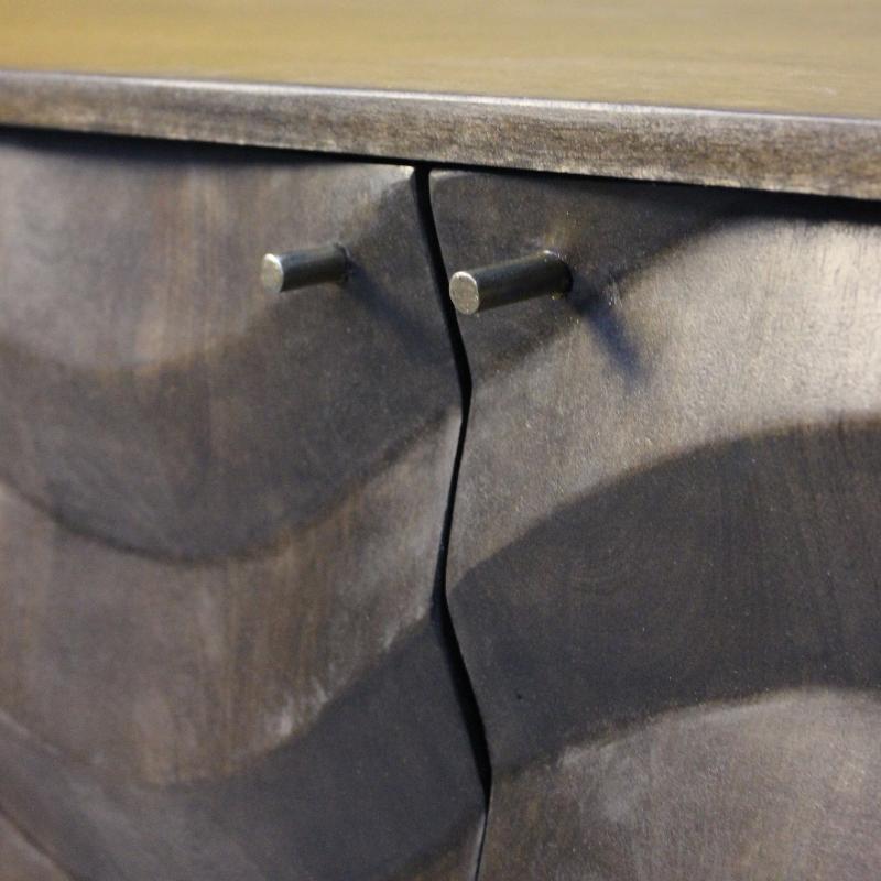 Close-up of a dark wood cabinet door with two round metal knobs and a visible vertical seam, showing part of a wooden tabletop at the top.