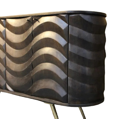 A mid-century modern sideboard cabinet with three doors featuring a sculpted, wavy metallic pattern in dark silver and black, supported by angled metal legs against a textured beige wall.