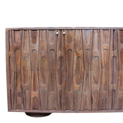 A mid-century modern wooden sideboard cabinet with vertically aligned wavy carved doors, featuring two small round brass knobs and a round metal footrest visible at the bottom, set against a plain white background.