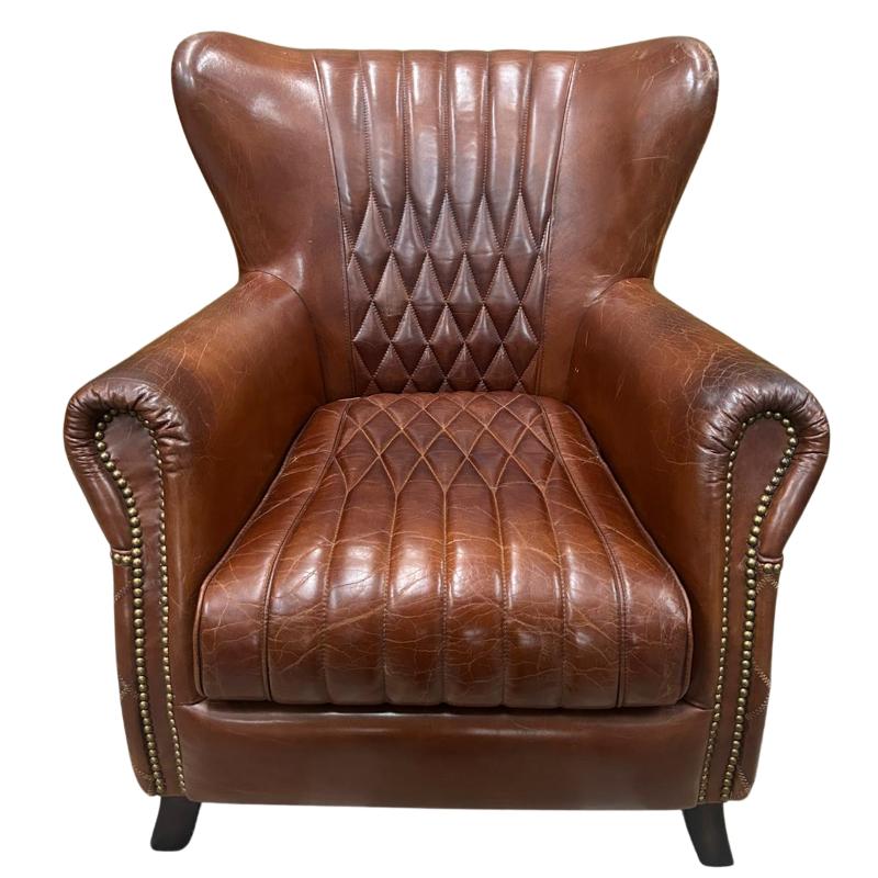 A classic brown leather wingback armchair with diamond-quilted tufting on the backrest and seat, rolled arms with nailhead trim, and dark legs, shown against a plain white background.