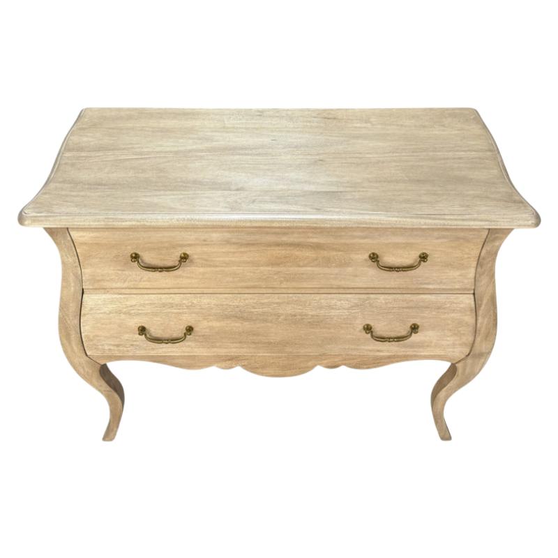 A light beige wood chest of drawers with two curved drawers, brass handles, and cabriole-style legs, shown against a plain white background.