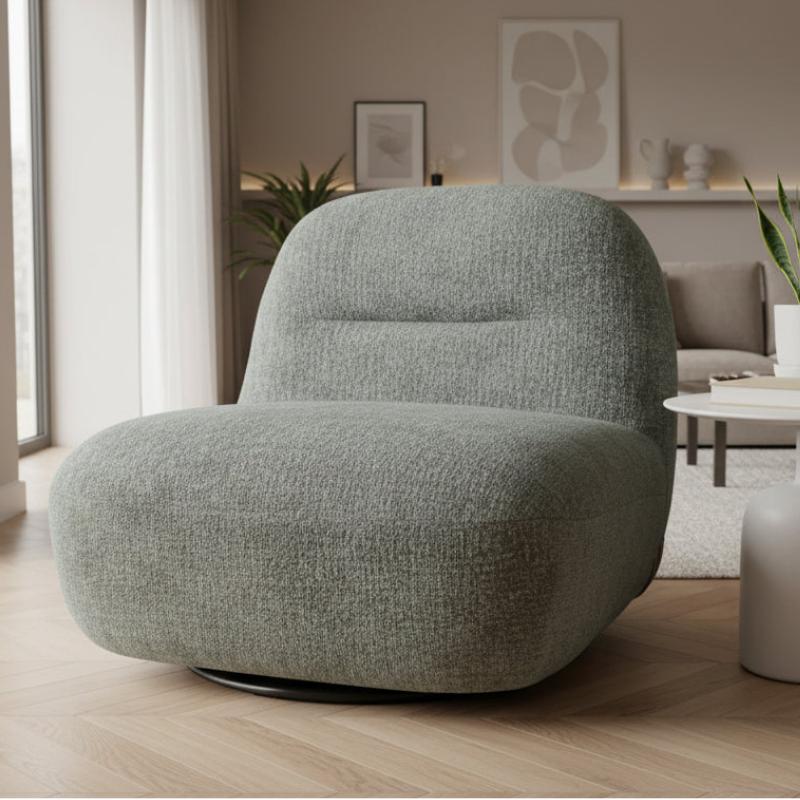 A modern low-profile swivel armchair with a rounded, cloud-like silhouette upholstered in a textured light sage green bouclé fabric, set in a bright, contemporary living room.