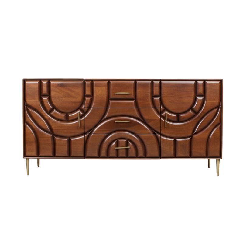 Mid-century modern wooden sideboard with carved geometric patterns, three drawers, and brass legs on a light gray background.