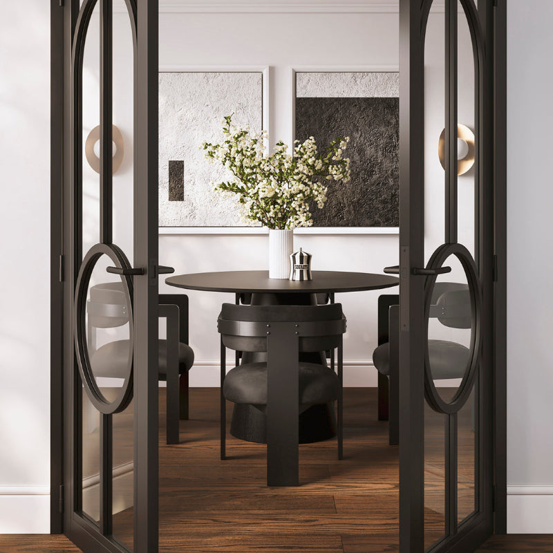 Dining room with a round table and chairs, framed by a decorative glass door.