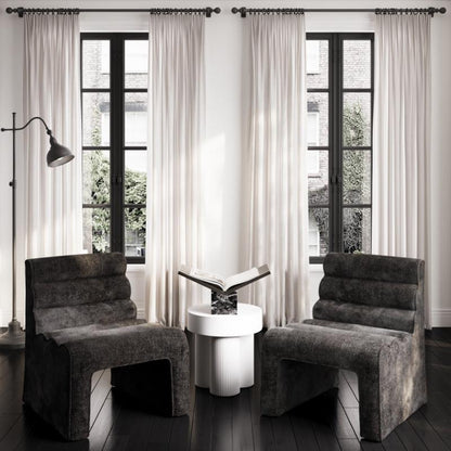 Modern interior with two gray cushioned chairs and a white side table.