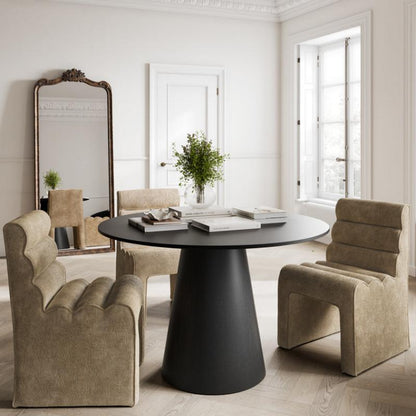 A modern dining set in a bright, classic room with white walls and ornate molding. The set includes a round black table on a tapered base, flanked by two beige upholstered armchairs and a matching armchair at the back, with a tall decorative mirror on the left.