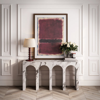 Marble console table with abstract painting and lamp in a room with white paneled walls.