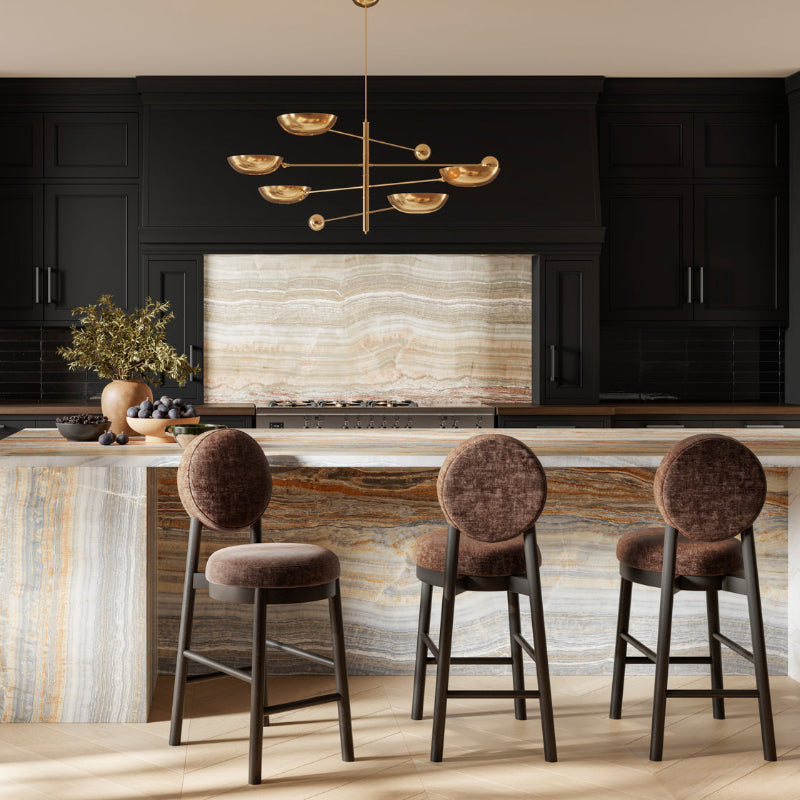 Modern kitchen with black cabinets, marble island, and gold chandelier.