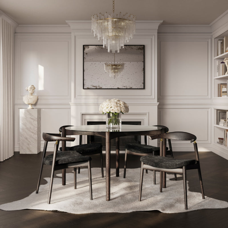 Dining room with a round table and chairs, featuring a chandelier and framed artwork on the wall.