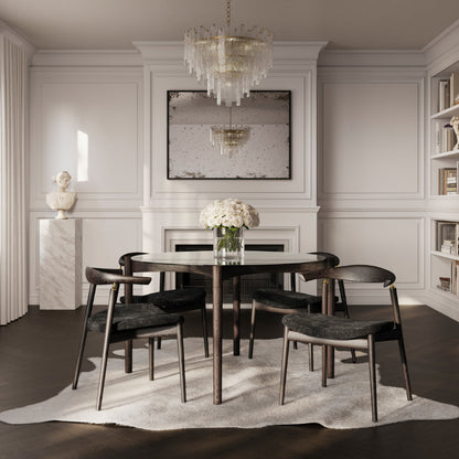 Dining room with a round table and chairs, featuring a chandelier and framed artwork on the wall.