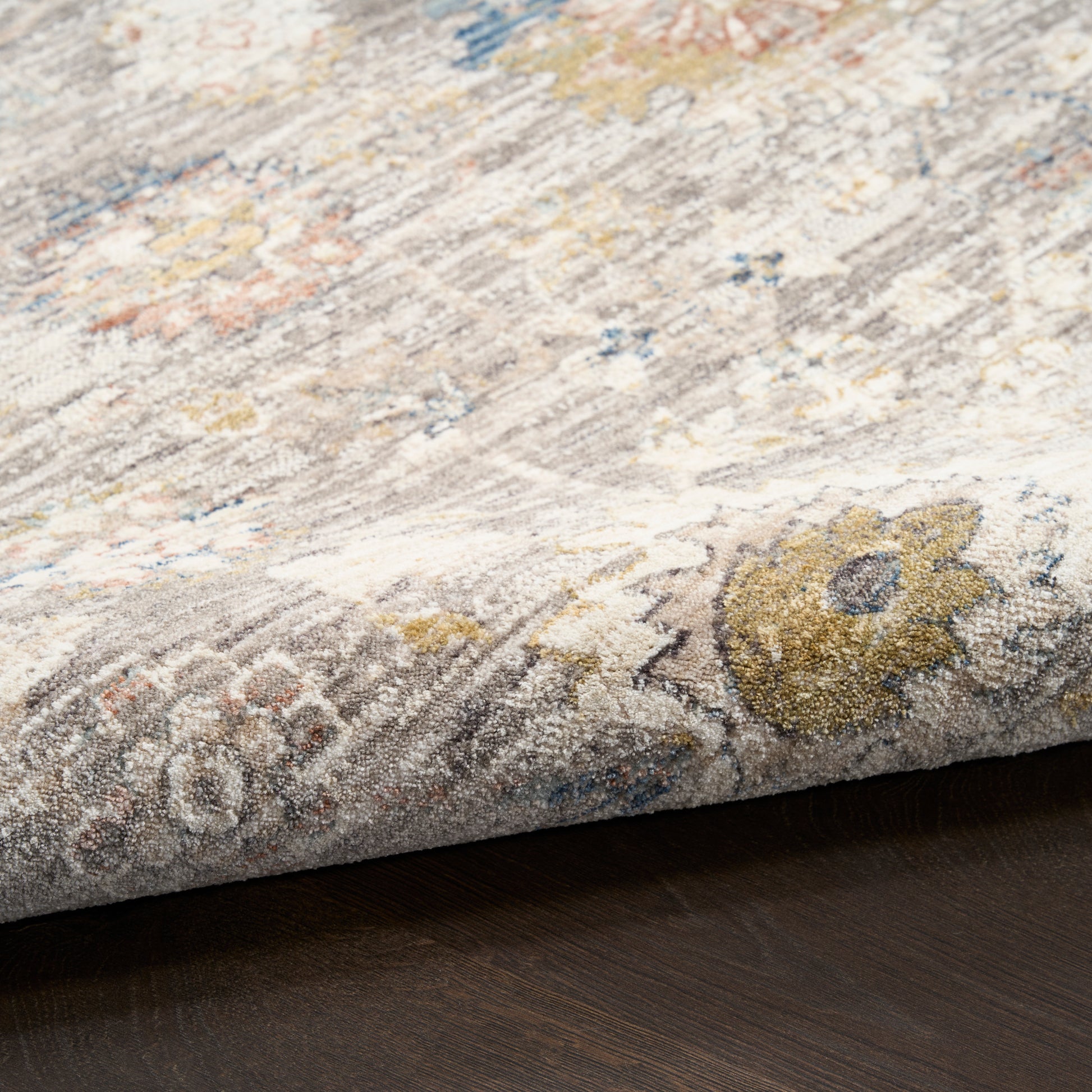 Close-up of a textured area rug with floral patterns on a wooden floor.