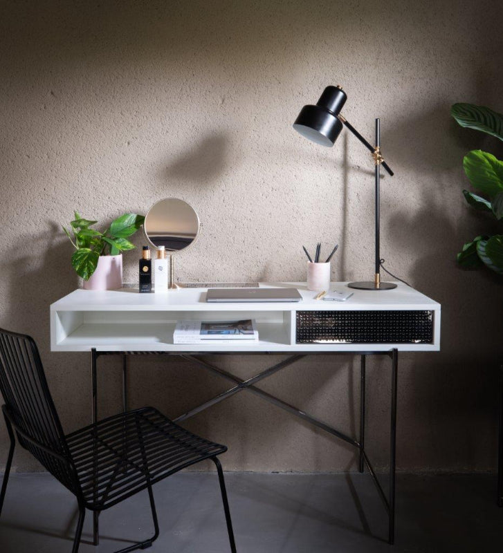 Modern white desk with black chair and lamp against a neutral wall.