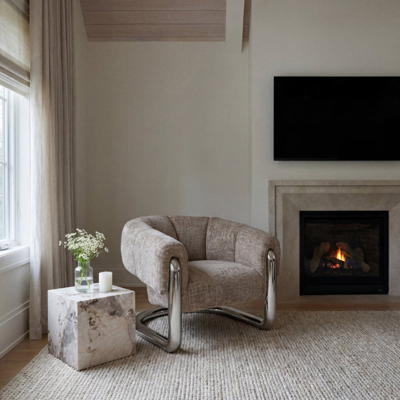 Modern living room with a beige armchair, marble side table, and fireplace.