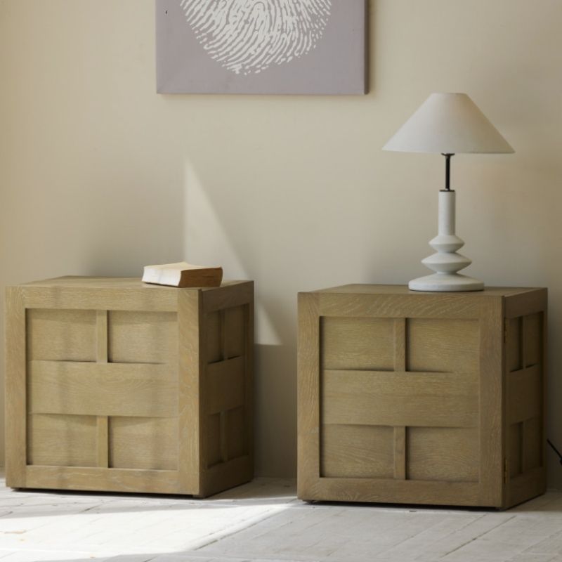 Two wooden nightstands with a lamp and book against a beige wall.