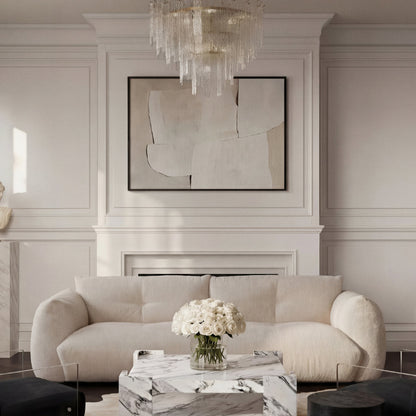 Modern living room with a white sofa, marble coffee table, and abstract art on the wall.