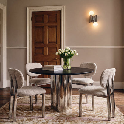 Dining room with a round metallic table and four chairs, featuring a vase of flowers.