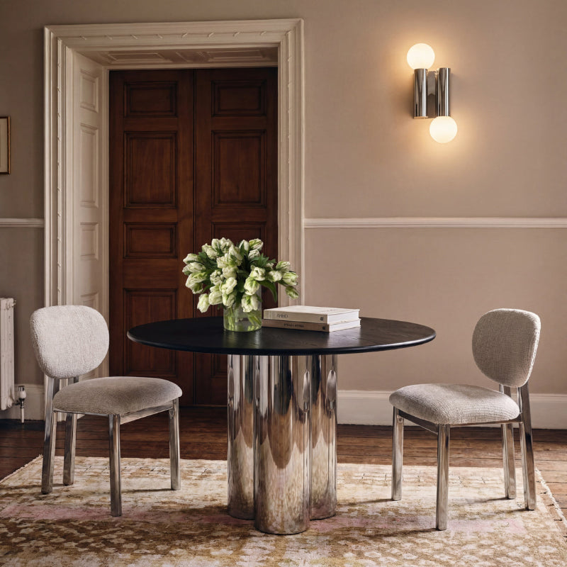 Dining room with a round table and chairs, featuring a vase of flowers and books.