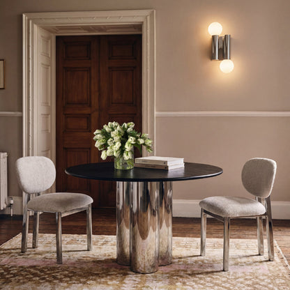 Dining room with a round table and chairs, featuring a vase of flowers and books.