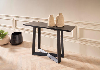 Modern black console table with decorative vases against a neutral wall.