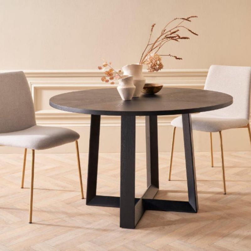 Round dining table with two chairs in a room with beige walls and wooden floor.